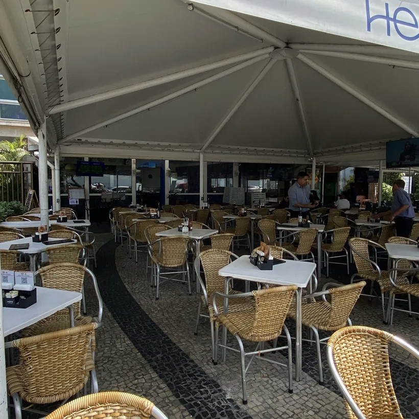 Salão do Hera com mesas sob o toldo, visto da entrada