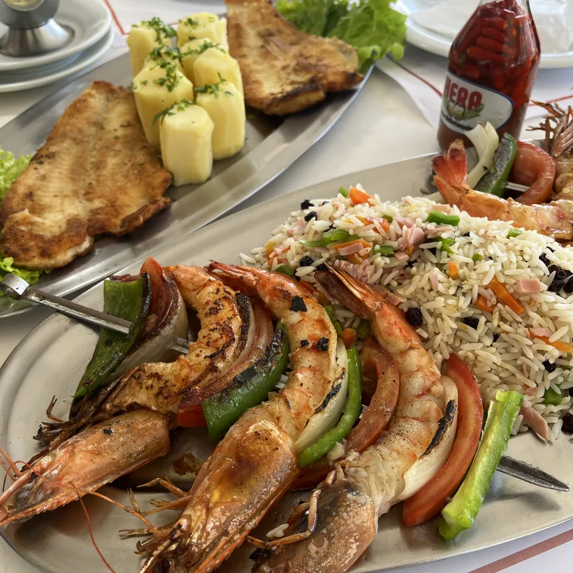 Camarão grelhado e peixe servidos com arroz à grega