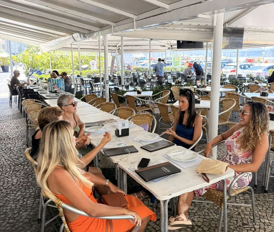 Mesas na calçada do Hera com a orla de Copacabana ao fundo